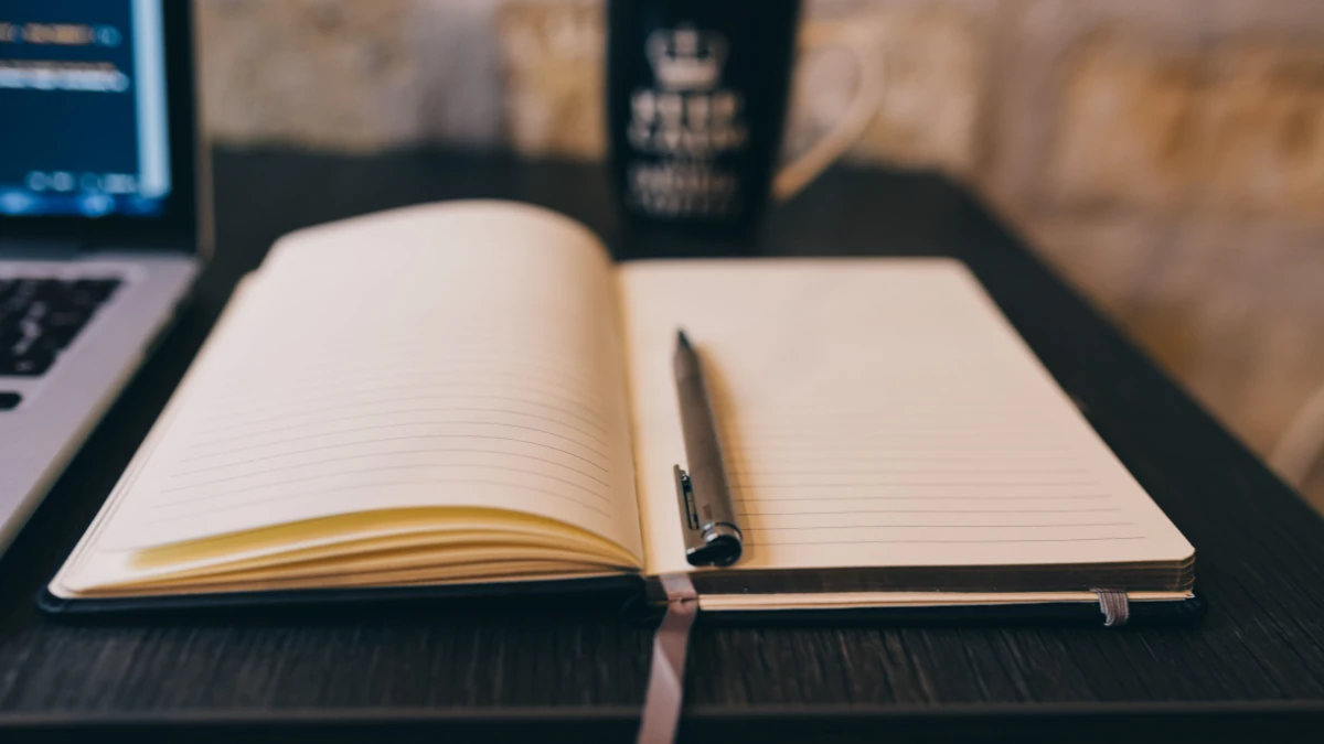 Un bureau d'écrivain organisé, avec un clavier, un carnet des notes et un café, illustrant la méthode pour écrire un livre